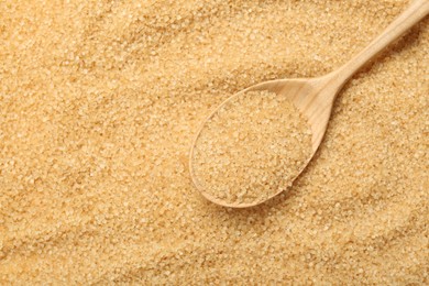 Photo of Spoon on granulated brown sugar, top view