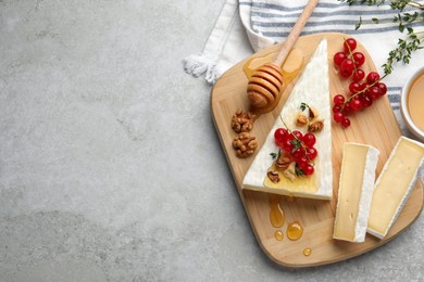 Photo of Brie cheese served with currants, walnuts and honey on light table, flat lay. Space for text