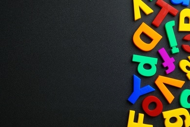 Photo of Plastic magnetic letters on black background, top view with space for text
