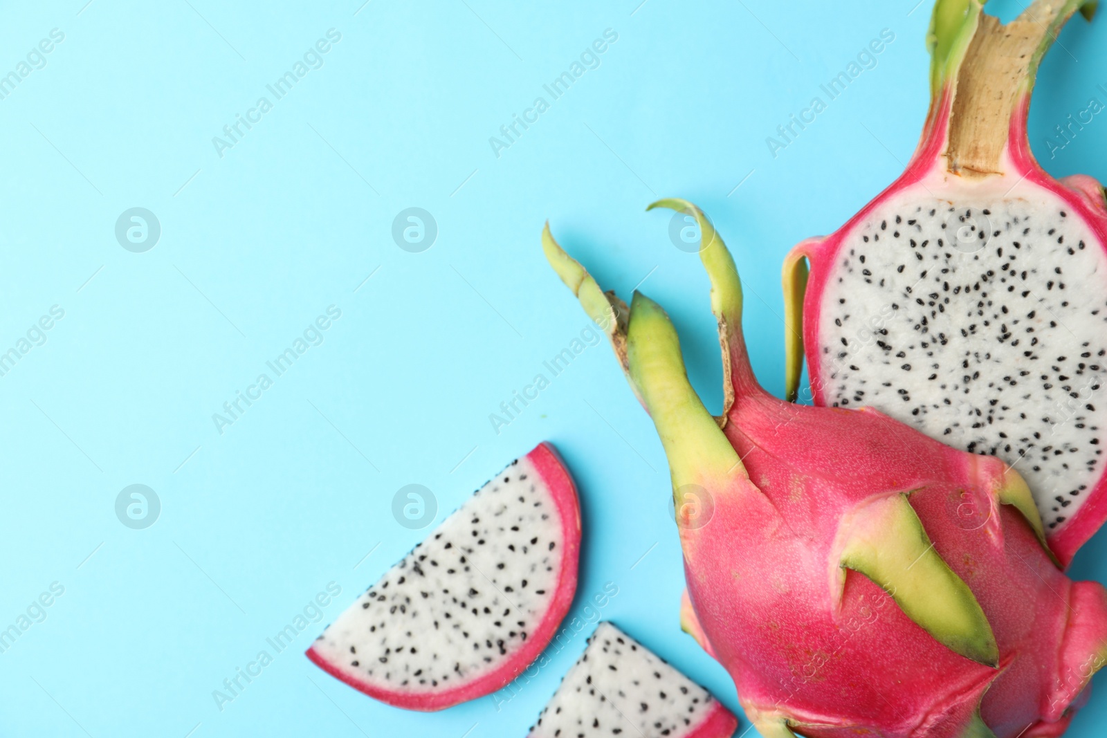 Photo of Delicious cut dragon fruit (pitahaya) on light blue background, flat lay. Space for text