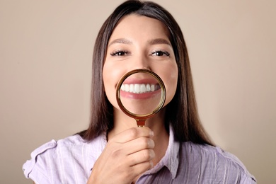 Photo of Young woman with healthy teeth and magnifier on color background