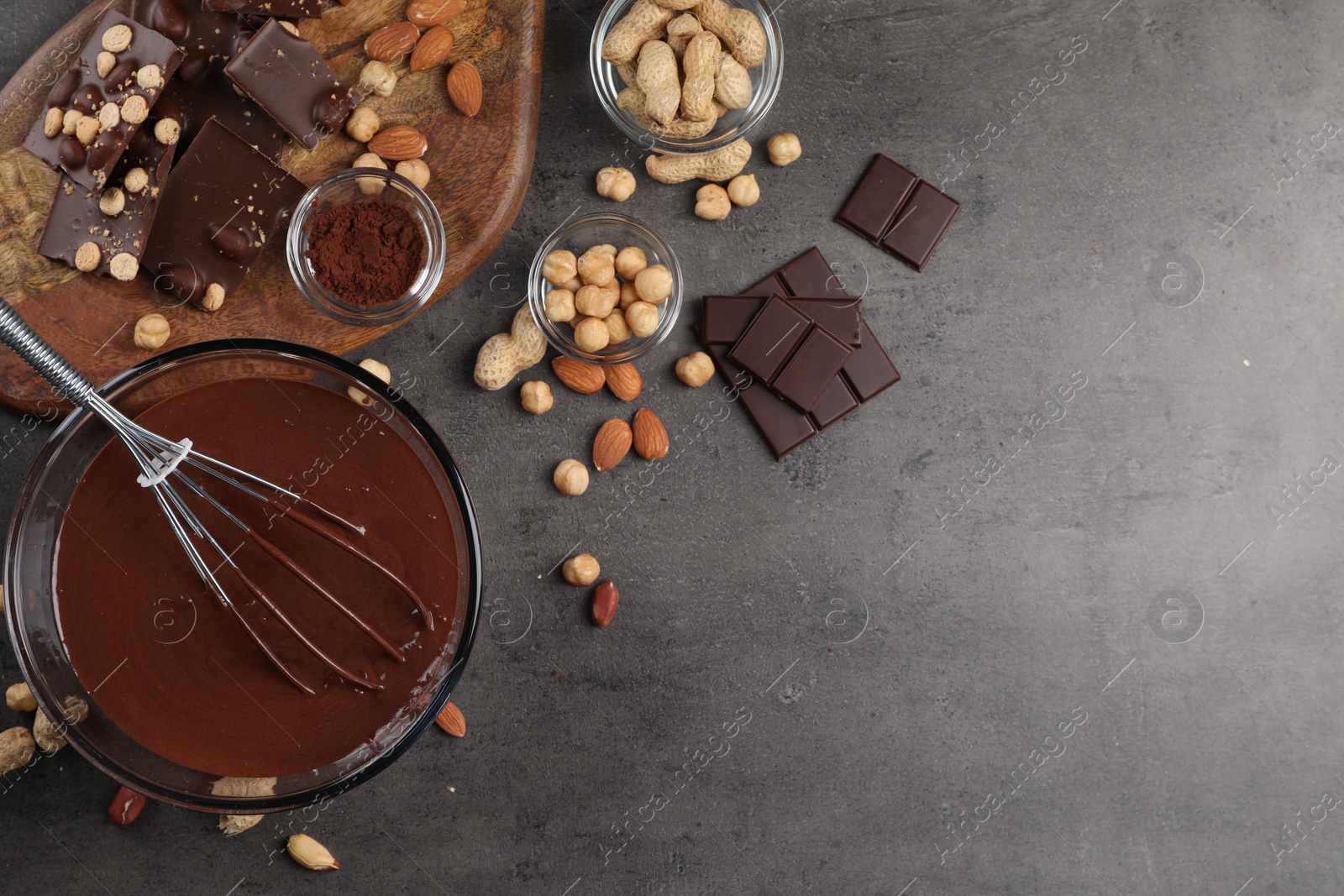 Photo of Bowl of chocolate cream, whisk, and nuts on gray table, flat lay. Space for text