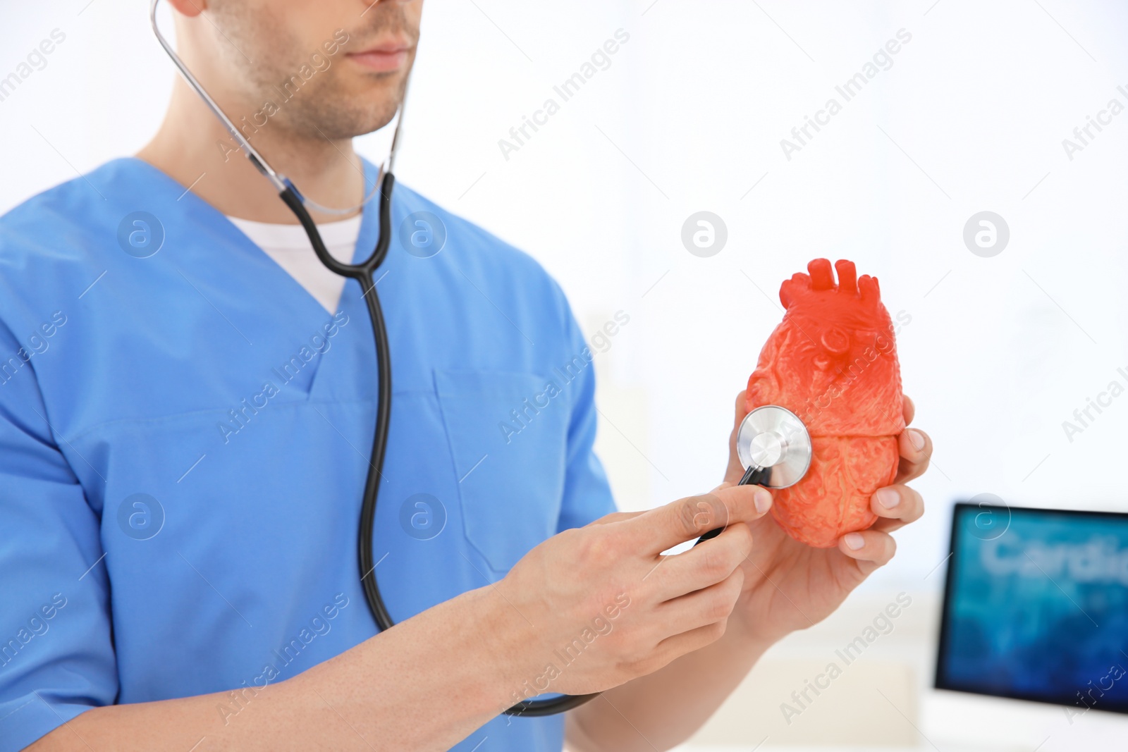 Photo of Male doctor with heart model and stethoscope in clinic. Cardiology center