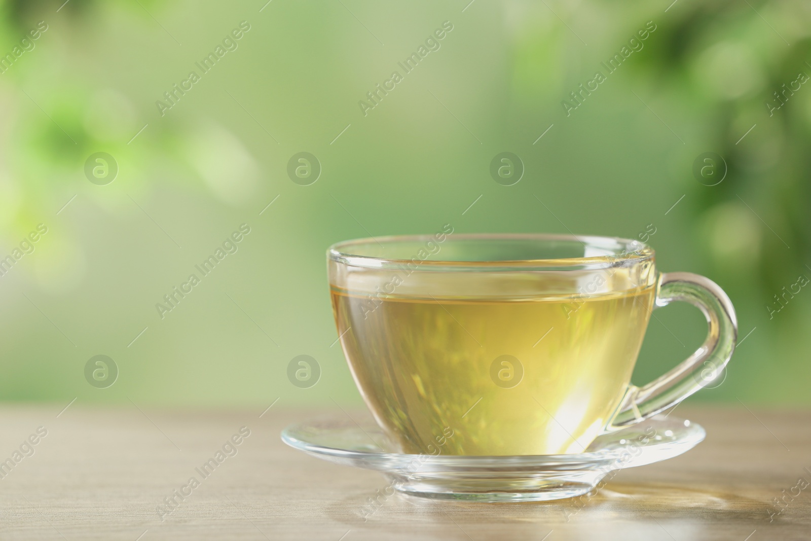 Photo of Glass cup of fresh herbal tea on table. Space for text