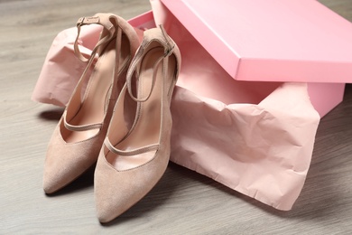Pair of beautiful shoes and box on wooden background