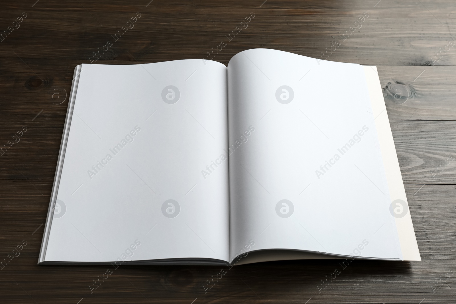 Photo of Open blank paper brochure on wooden table. Mockup for design