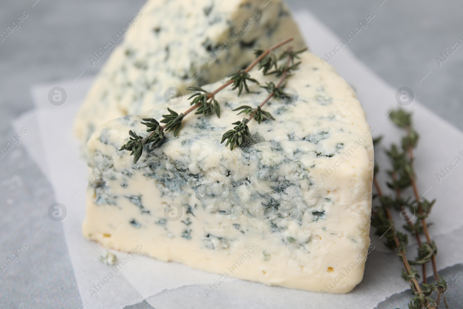 Photo of Tasty blue cheese with thyme on grey table, closeup