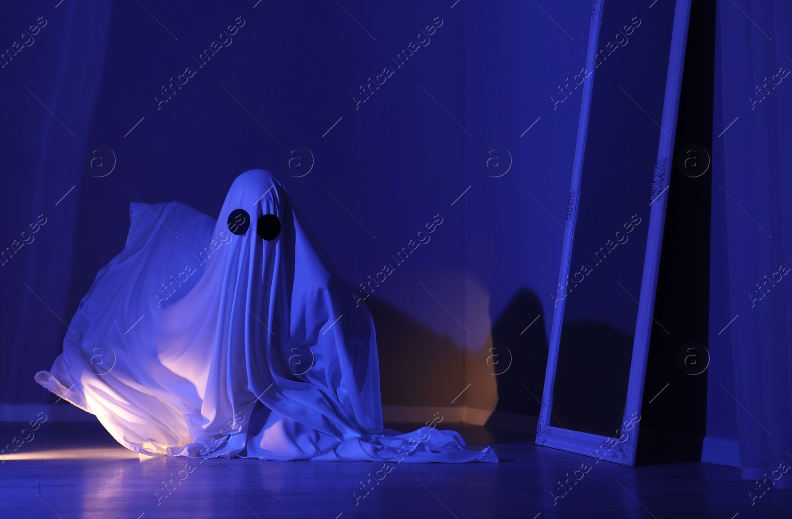 Photo of Creepy ghost. Woman covered with sheet in blue light