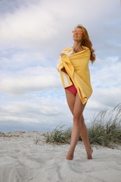 Photo of Beautiful woman in bikini with beach towel on sand