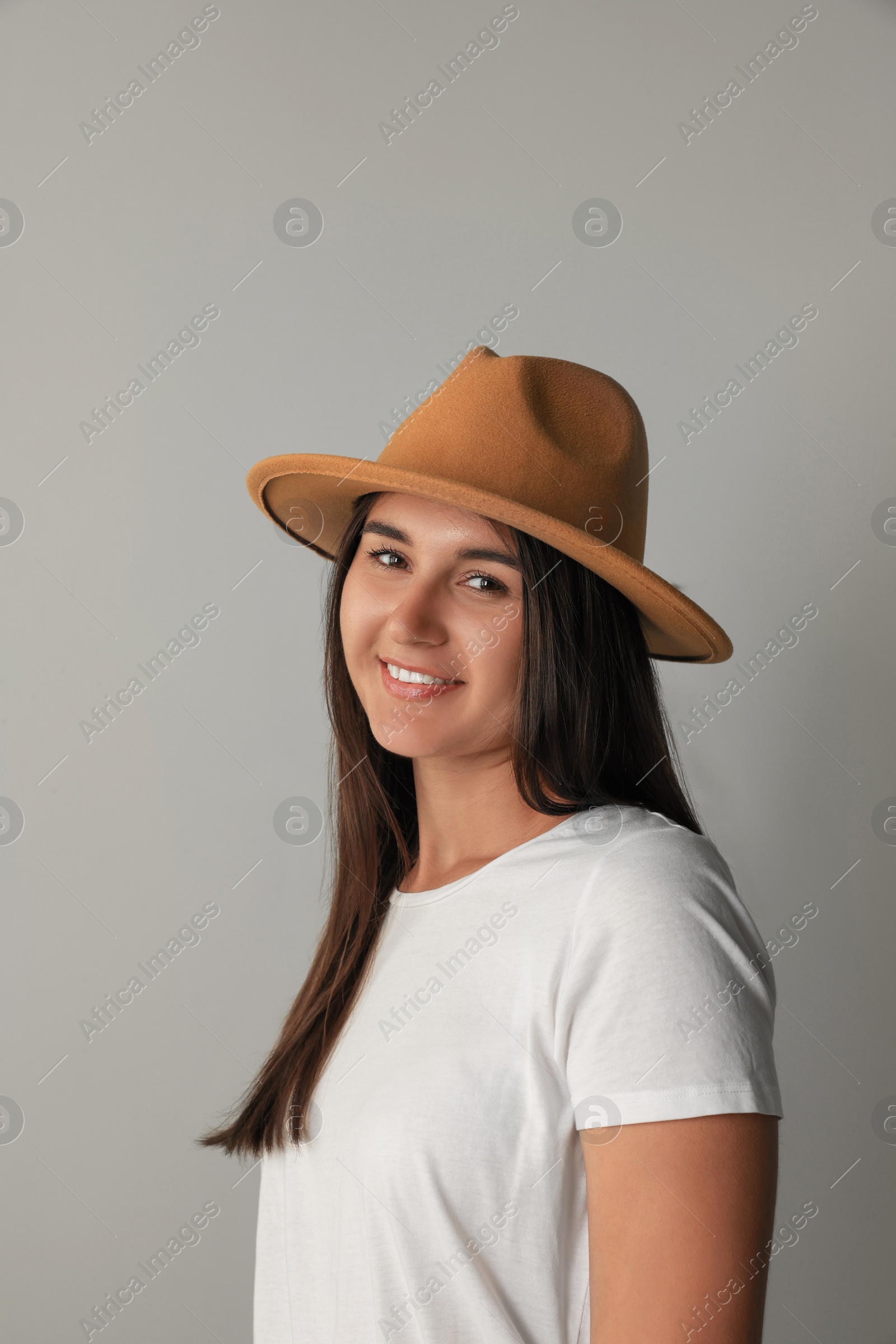 Photo of Smiling young woman in stylish outfit on light grey background