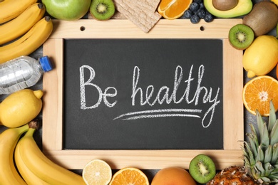 Flat lay composition with fruits and words "BE HEALTHY" on blackboard. Concept of weight loss