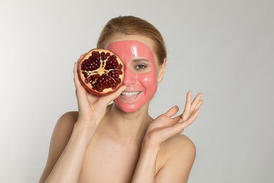 Photo of Young woman with pomegranate face mask and fresh fruit on light grey background