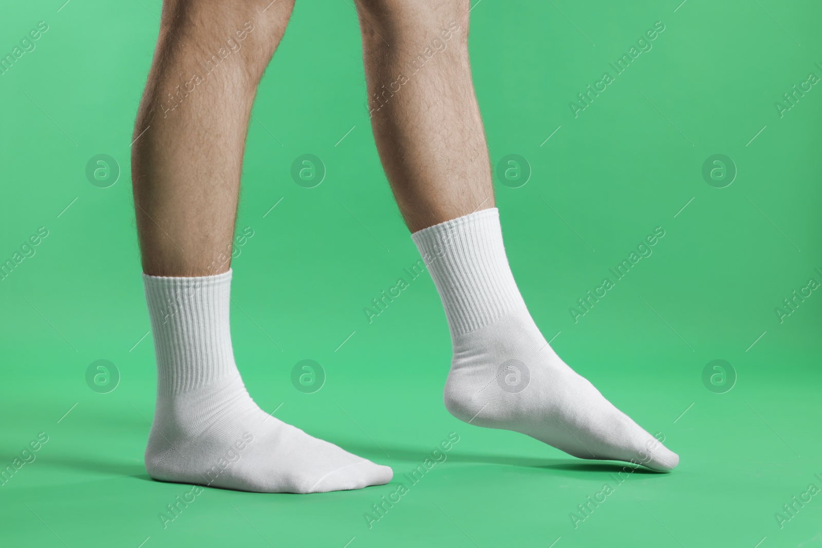 Photo of Man in stylish white socks on green background, closeup