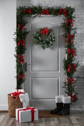 Photo of Stylish hallway interior with decorated door and Christmas gifts