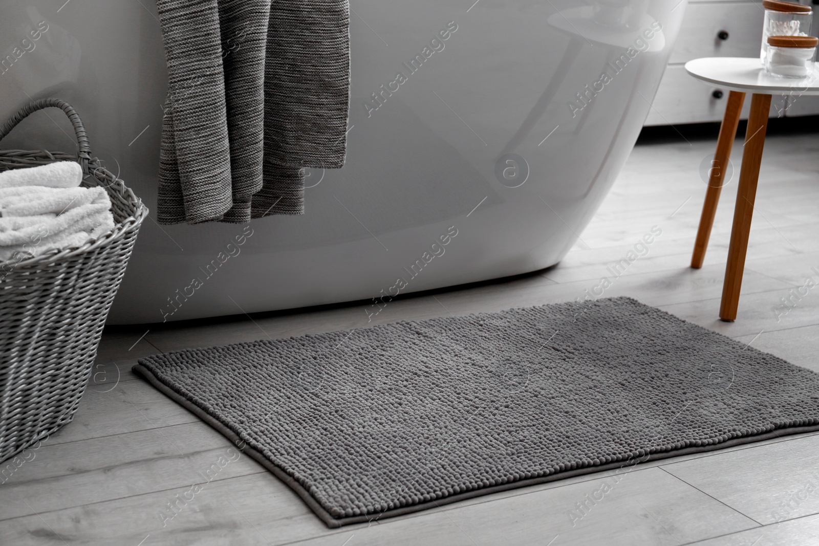Photo of Soft grey mat on floor near tub in bathroom. Interior design