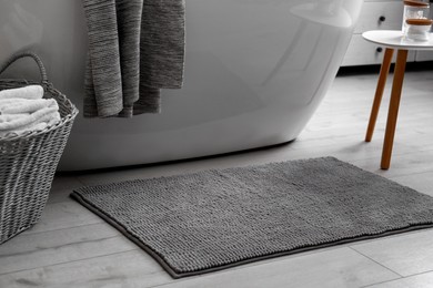 Soft grey mat on floor near tub in bathroom. Interior design