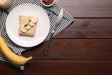 Photo of Toast with tasty nut butter, banana slices and almond flakes on wooden table, flat lay. Space for text