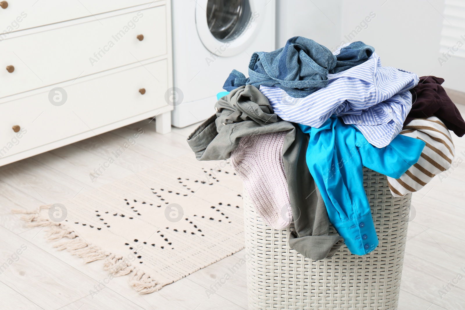 Photo of Plastic laundry basket overfilled with clothes in bathroom