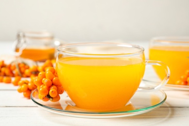 Photo of Delicious sea buckthorn tea and fresh berries on white wooden table