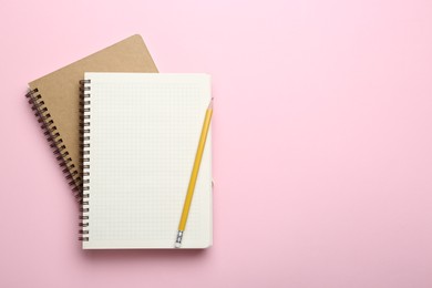 Photo of Notebooks and pencil on pink background, top view. Space for text