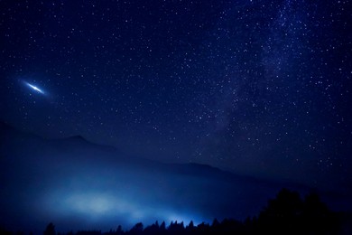Image of Sky with twinkling stars over mountains at night