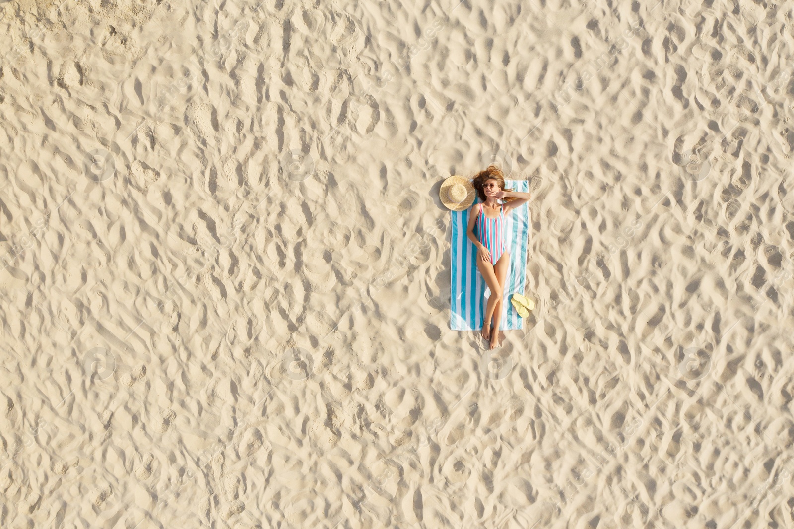 Image of Woman sunbathing on beach towel at sandy coast, aerial view. Space for text