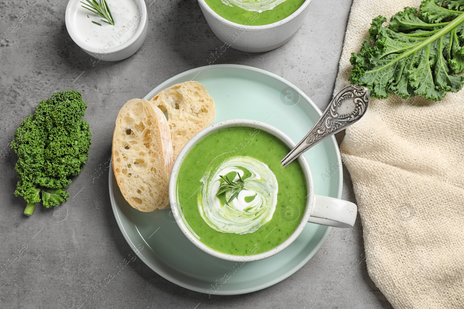 Photo of Tasty kale soup served on grey table, flat lay