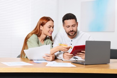 Photo of Couple calculating taxes at table in room