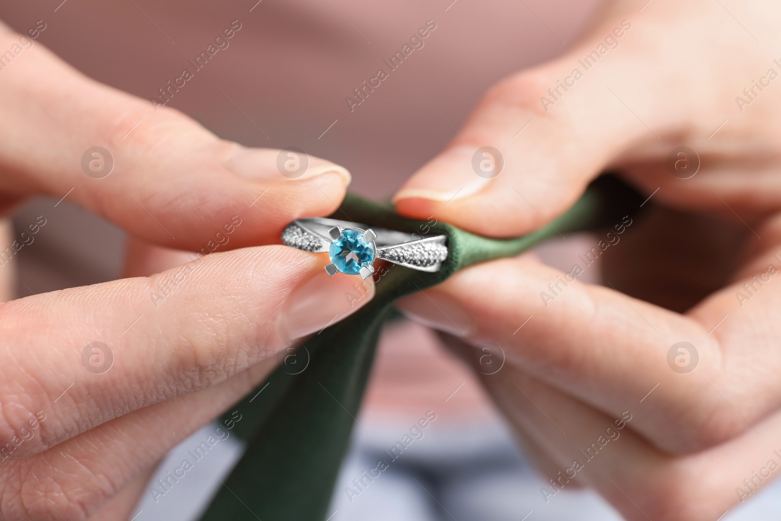 Photo of Jeweler cleaning topaz ring with microfiber cloth, closeup