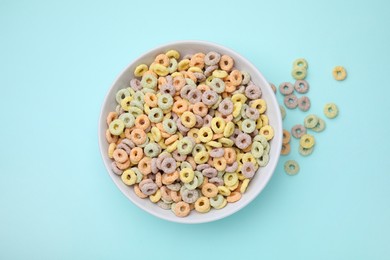 Photo of Tasty cereal rings in bowl on light blue table, top view