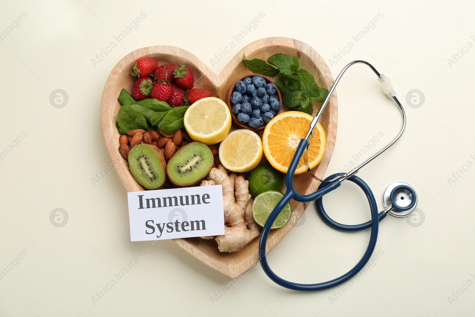 Photo of Heart shaped tray of healthy products, stethoscope and card with text Immune System on beige background, flat lay