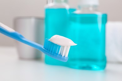 Photo of Toothbrush with paste near mouthwash on blurred background, closeup