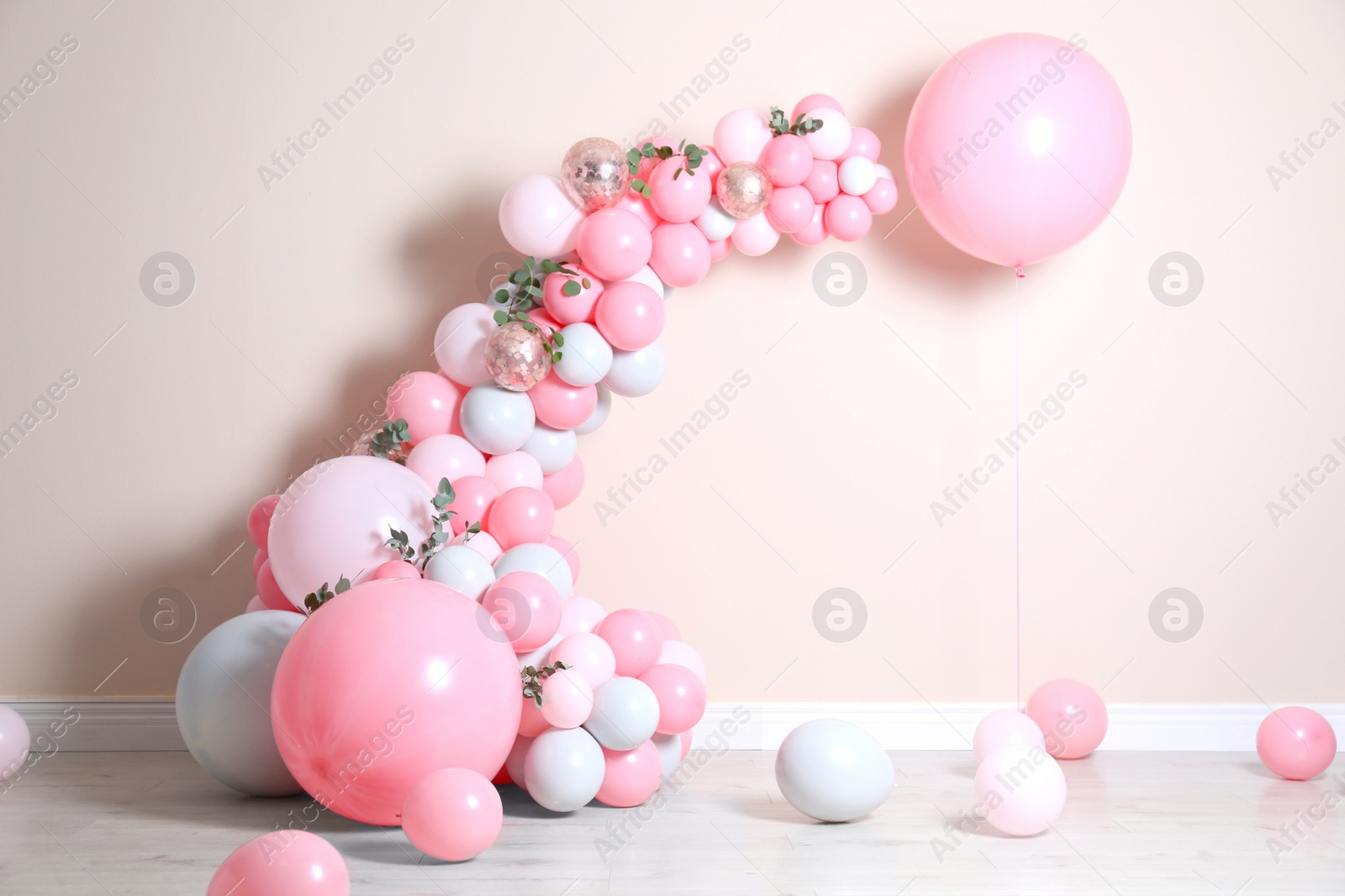 Photo of Beautiful composition with balloons and green leaves near beige wall