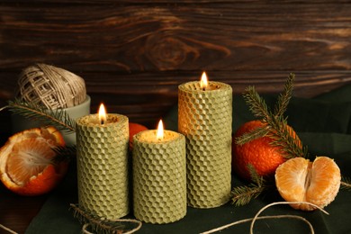 Photo of Beautiful burning beeswax candles, rope and tangerines on table