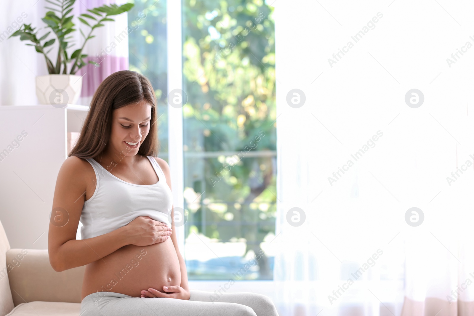 Photo of Pregnant woman sitting on sofa at home