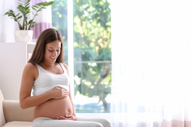 Pregnant woman sitting on sofa at home