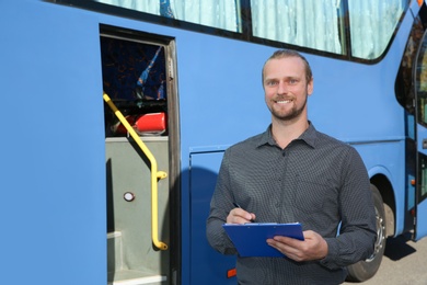 Professional driver with clipboard near bus. Passenger transportation