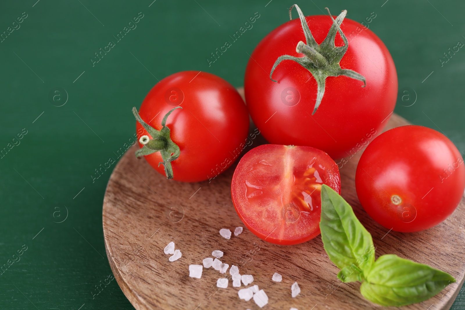 Photo of Whole and cut tomatoes on green wooden table, closeup