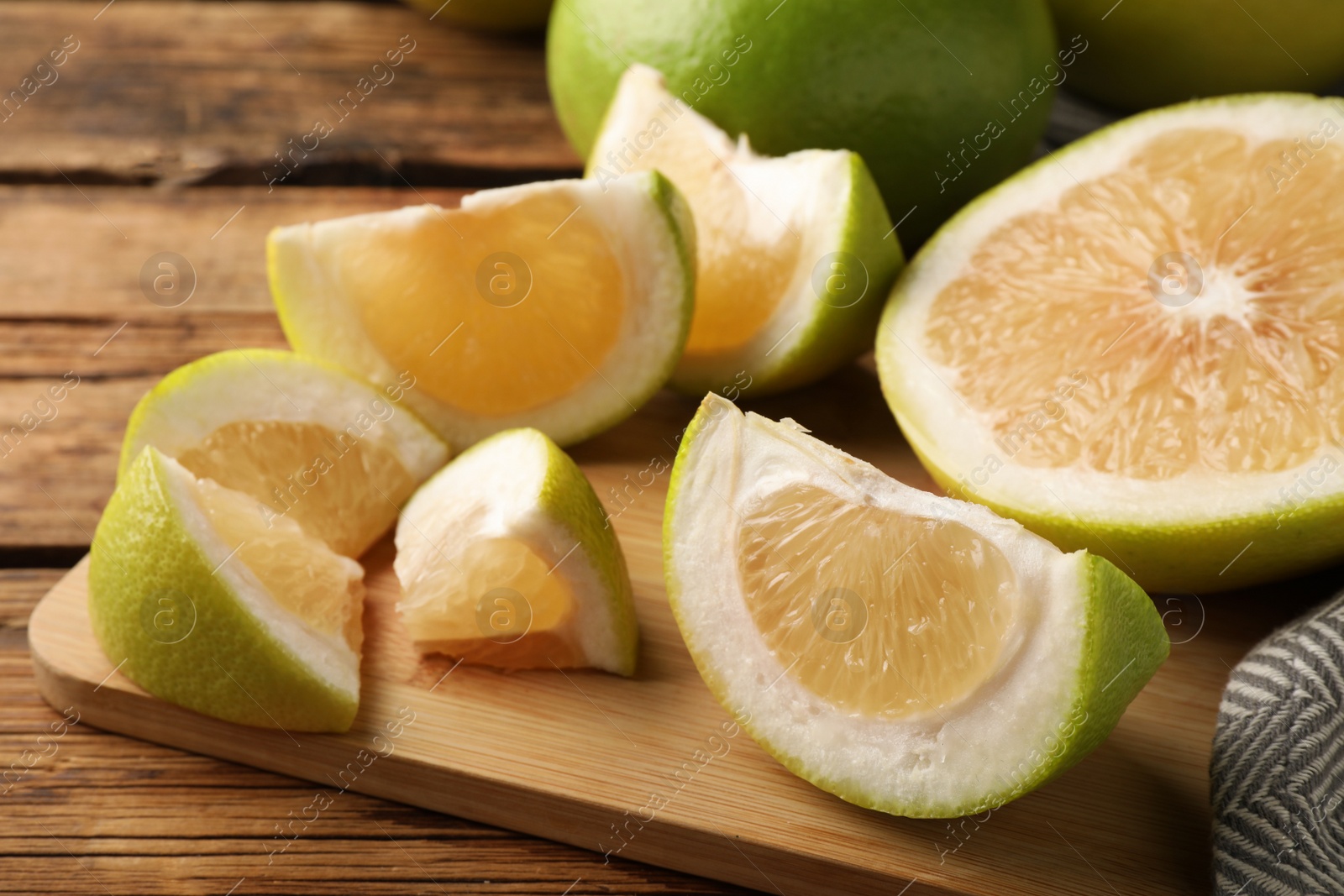 Photo of Sliced fresh sweetie fruits on wooden board, closeup