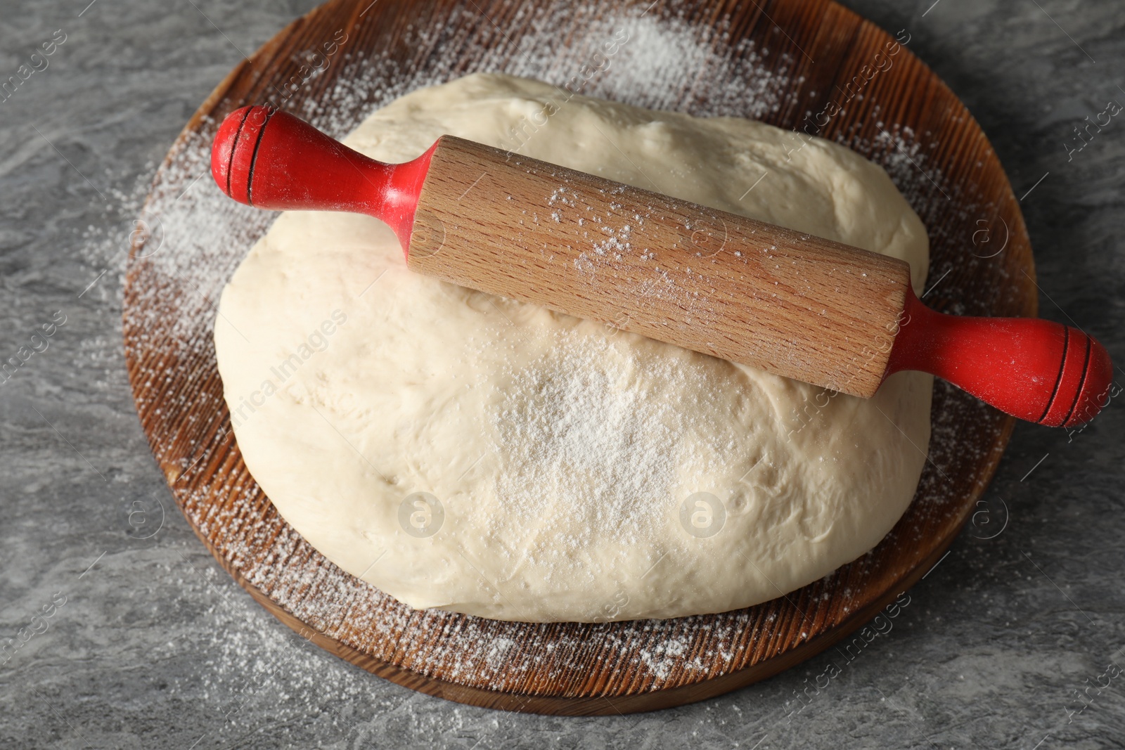 Photo of Raw dough and rolling pin on grey table