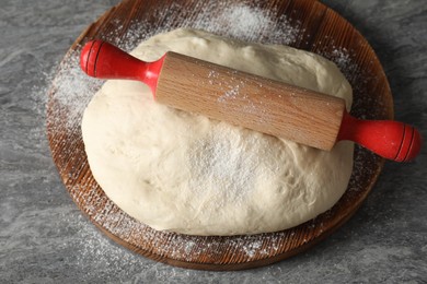 Photo of Raw dough and rolling pin on grey table