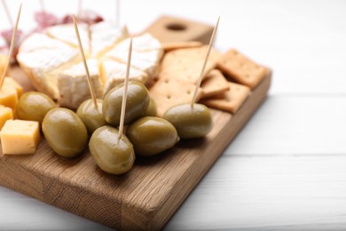 Toothpick appetizers. Olives on wooden board, closeup view with space for text