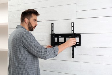 Photo of Man installing TV bracket on wall indoors