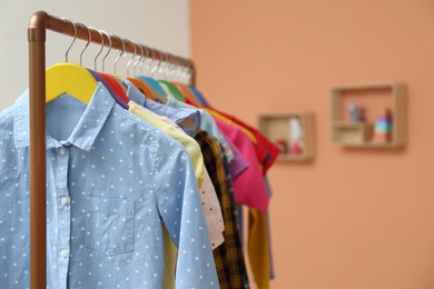 Photo of Different child's clothes hanging on rack indoors, closeup