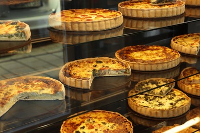 Different delicious quiches on counter in bakery shop