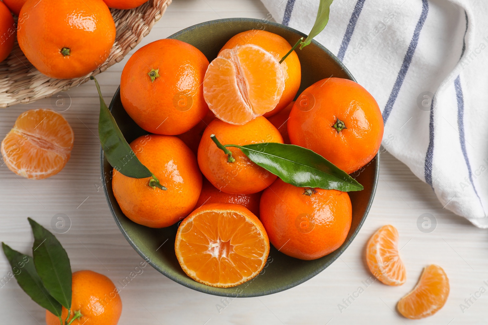 Photo of Delicious tangerines with green leaves on white wooden table, flat lay