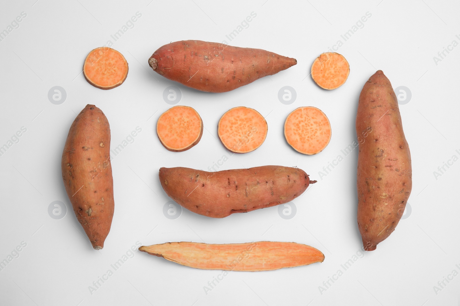 Photo of Cut and whole sweet potatoes on white background, top view
