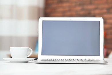 Laptop with blank screen on table indoors. Space for text