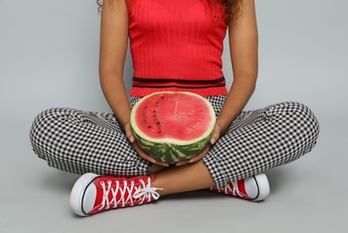 Photo of Beautiful young African American woman with half of watermelon on grey background, closeup