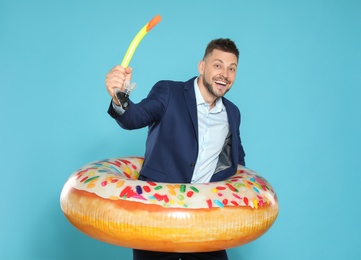 Photo of Funny businessman with bright inflatable ring on blue background